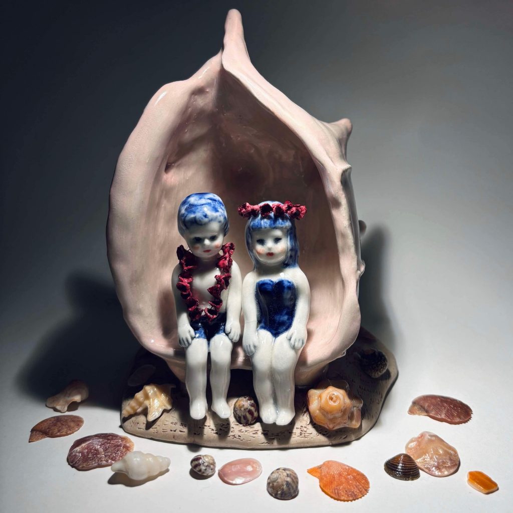 Keramikfigur föreställande två flickfigurer sitter i en snäcka omgivna av mindre snäckor